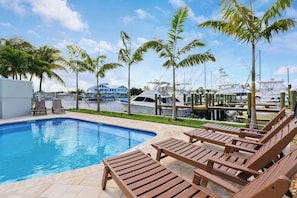 A swimming pool with lounge chairs, palm trees, and boats in the background. - Sailfish Suites 2 - pet friendly & waterfront!!! (Stuart)