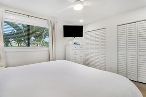 A bedroom with a bed, a TV mounted on the wall, a dresser, and a closet. - Sailfish Suites 2 - pet friendly & waterfront!!! (Stuart)