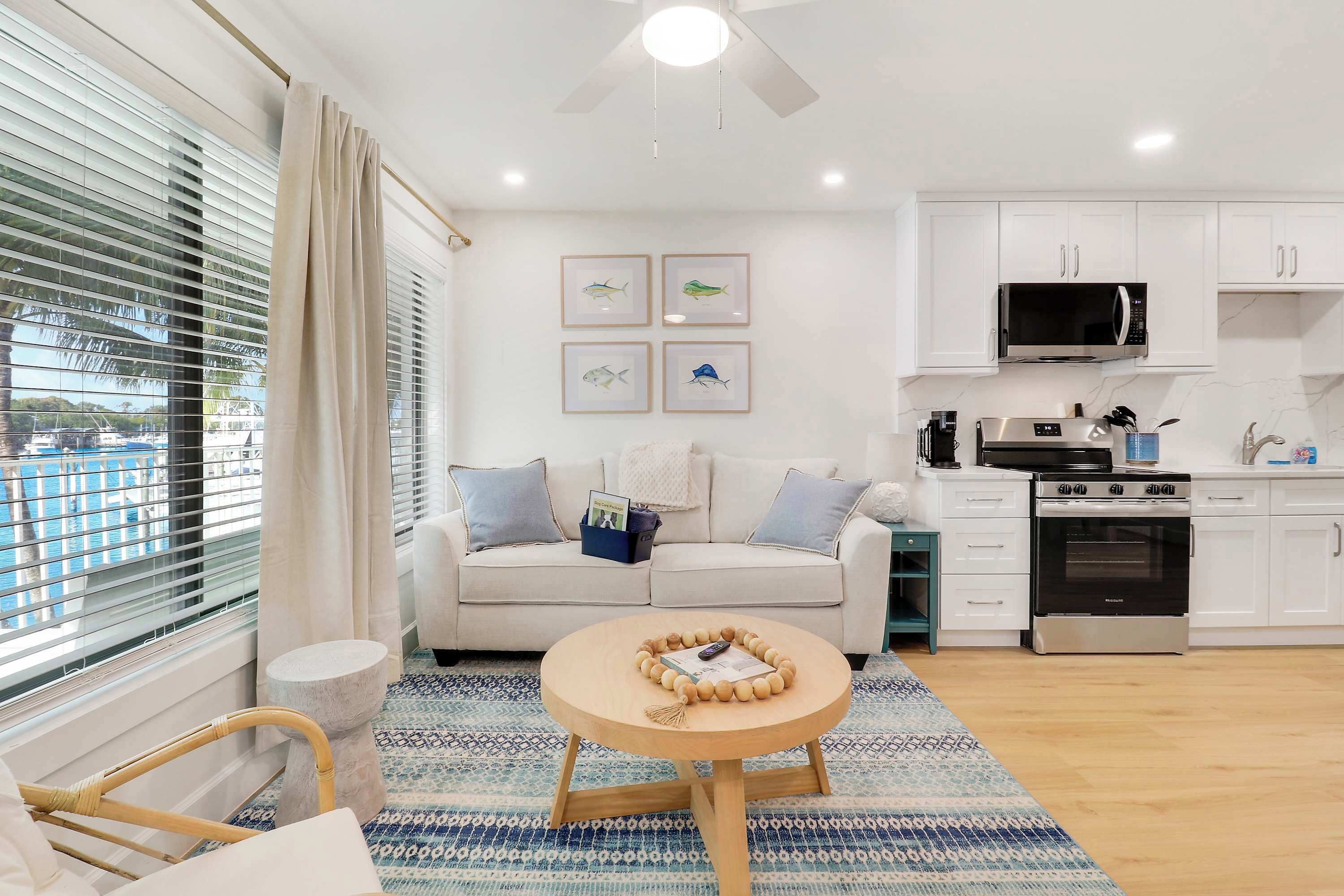 A modern kitchen with white cabinets, a microwave, and an oven. There is a round wooden table with a decorative item in the center.
