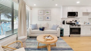 A modern kitchen with white cabinets, a microwave, and an oven. There is a round wooden table with a decorative item in the center. - Sailfish Suites - 11 - Waterfront (Stuart)