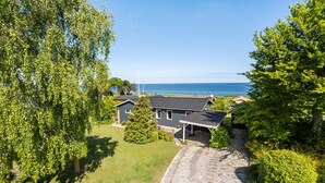 Ein Haus mit dunklem Dach, einer überdachten Veranda und Blick auf das Meer.