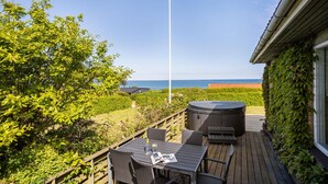 Eine Terrasse mit Sitzgelegenheit im Freien, einem Whirlpool und Blick auf das Meer.