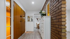 A hallway with wooden doors, a brick wall, and a white cabinet. - Tree-Lined Donvale Nature Family Getaway (Donvale)