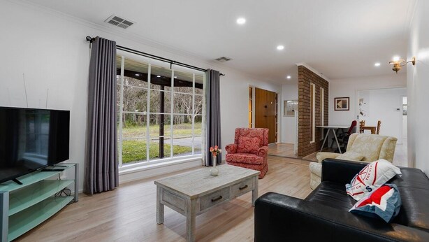 A modern living room with a flat-screen TV, a coffee table, and a leather sofa. - Tree-Lined Donvale Nature Family Getaway (Donvale)