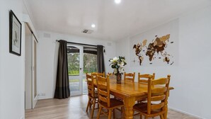 A dining area with a wooden table and chairs, a vase with flowers, and a world map on the wall. - Tree-Lined Donvale Nature Family Getaway (Donvale)
