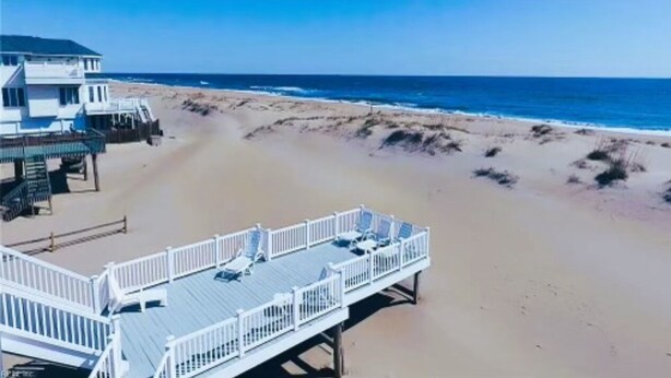 Una casa de playa con terraza y vista al océano.