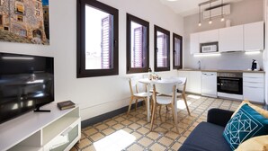 Un apartamento moderno con televisor, mesa de comedor, sillas y zona de cocina.