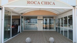 La entrada a Roca Chica, con fachada de vidrio, suelo de baldosas y dos esculturas de piedra.
