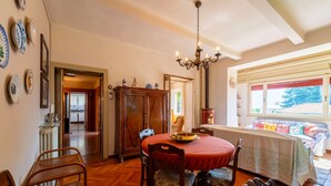 Un coin repas avec une table ronde, des chaises et un lustre. Une fenêtre offre une vue sur l’extérieur.