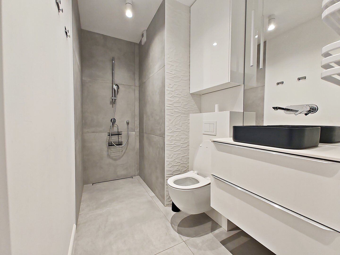 A modern bathroom with a shower, toilet, and a vanity with a mirror and sink.