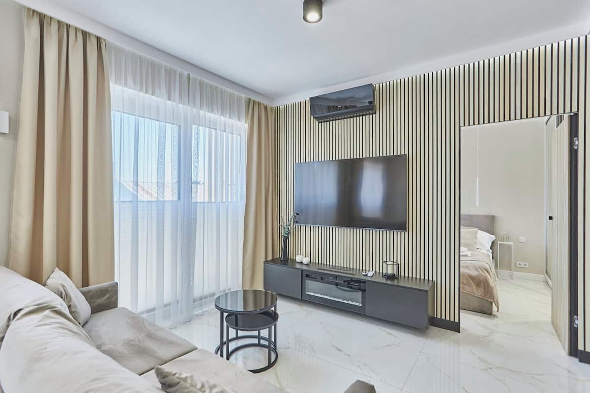 Ein modernes Hotelzimmer mit einem großen Bett, einer Couch, einem Fernseher und einem kleinen Tisch.