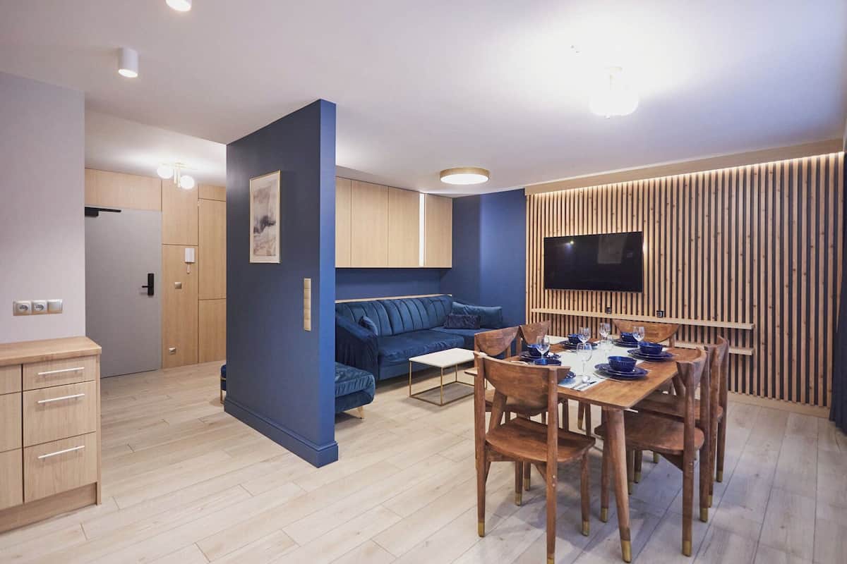 Eine moderne Wohnung mit Essbereich, einer Couch und einem an einer Holzvertäfelung befestigten Fernseher.