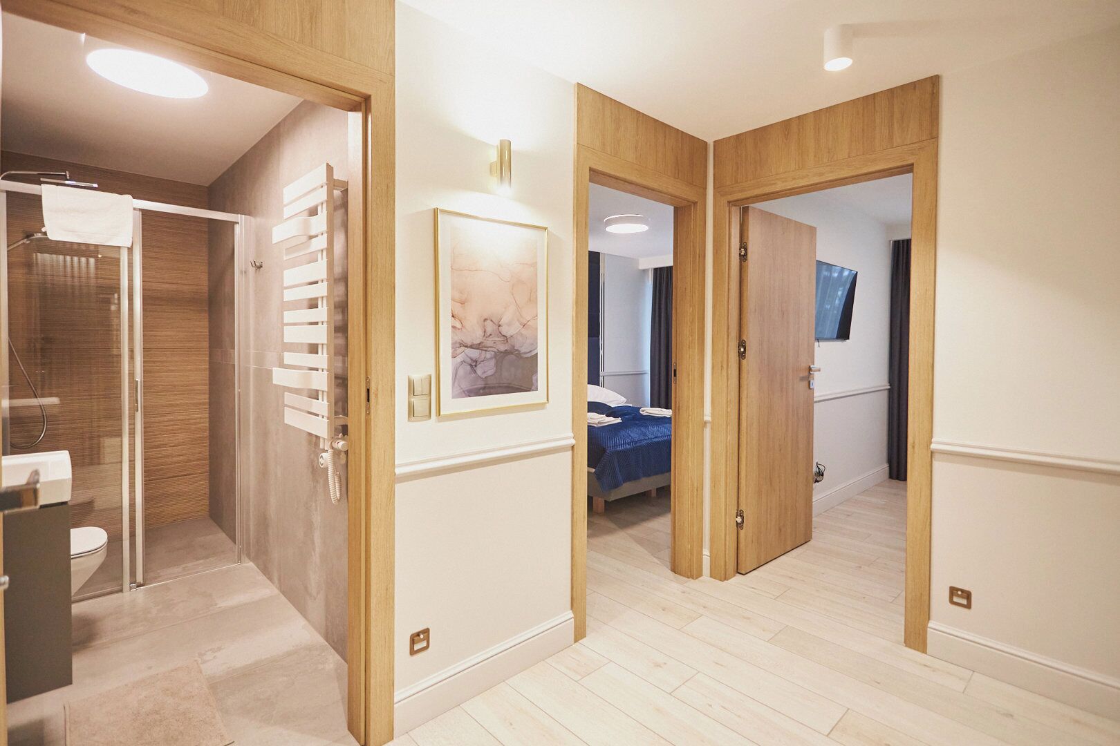 Une chambre d’hôtel moderne équipée d’une douche, d’un lit avec une couvre-lit bleue et d’un téléviseur fixé au mur.
