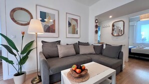 A modern living room with a grey sofa, a floor lamp, and a coffee table with fruit.
