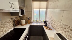 Cocina compacta con estufa, lavamanos y ventana con vistas.