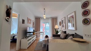 Una sala de estar moderna con un sofá, un televisor y un comedor con una mesa y sillas.