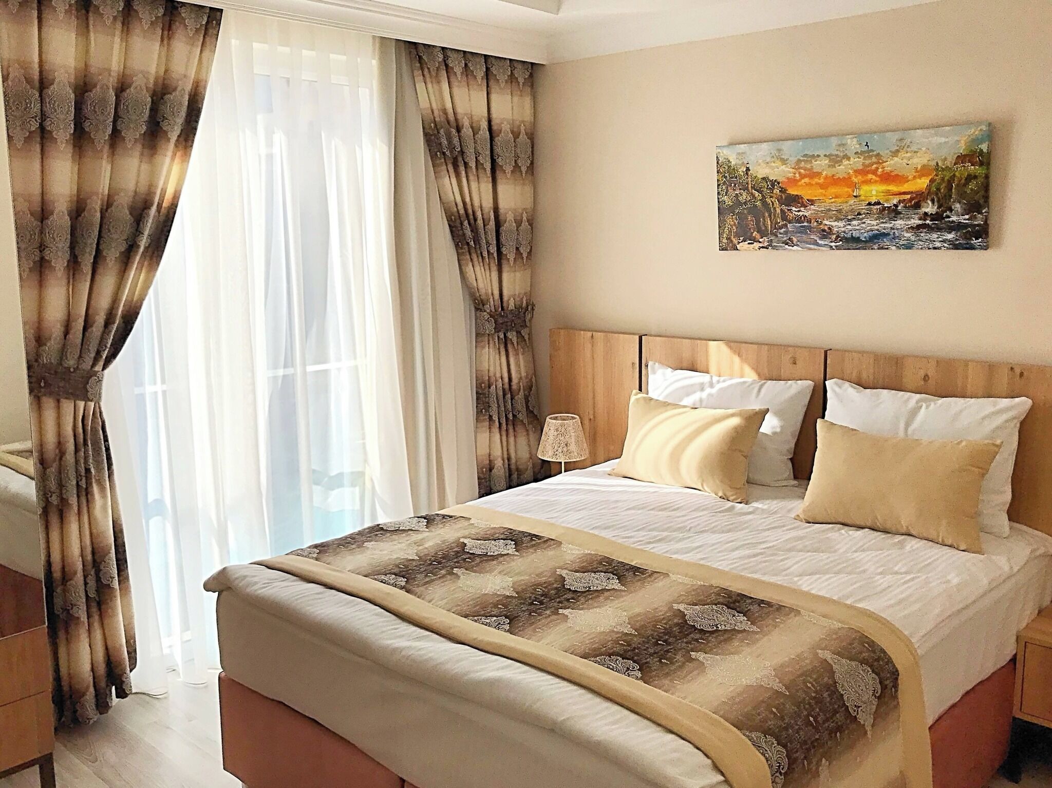 Um quarto com cama, cortinas, um quadro e uma mesa de cabeceira.