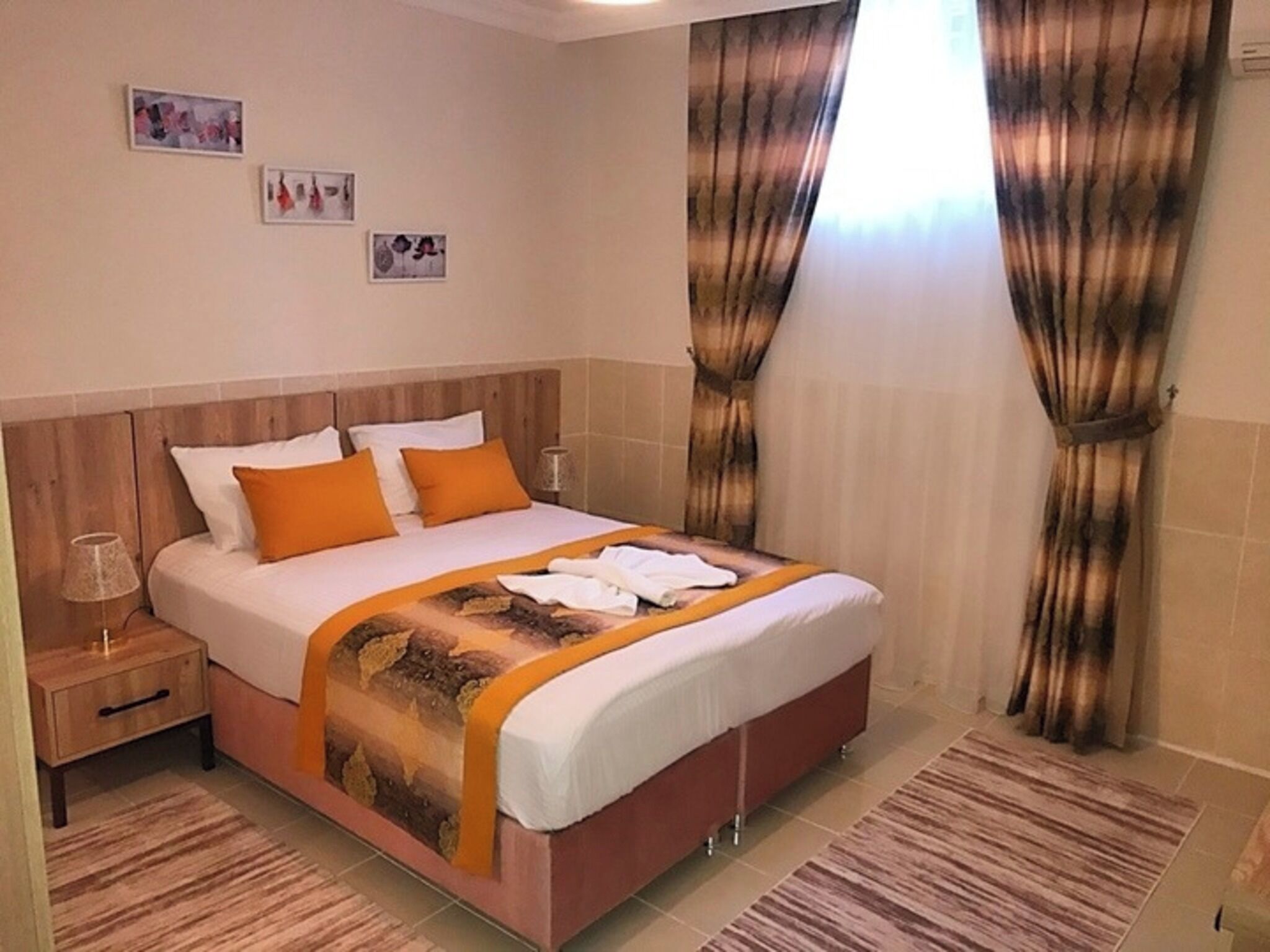 Quarto de hotel com cama, cortinas, mesa de cabeceira e decoração na parede.