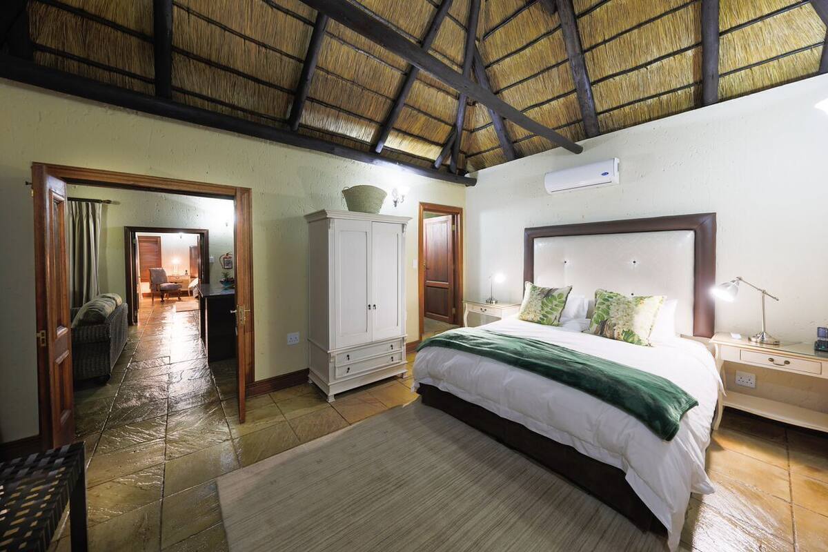 A bedroom with a large bed, a wardrobe, a nightstand, and a desk.