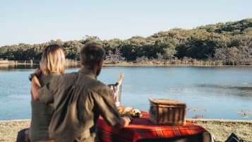 A couple sitting at a table by a lake with a picnic setup.