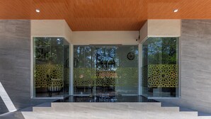 Un interior moderno con techo de madera, paredes de vidrio y una zona de estar con un separador decorativo.