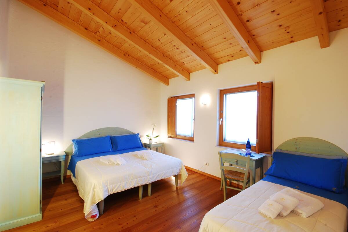 A bedroom with two beds, wooden flooring, and a sloped ceiling.