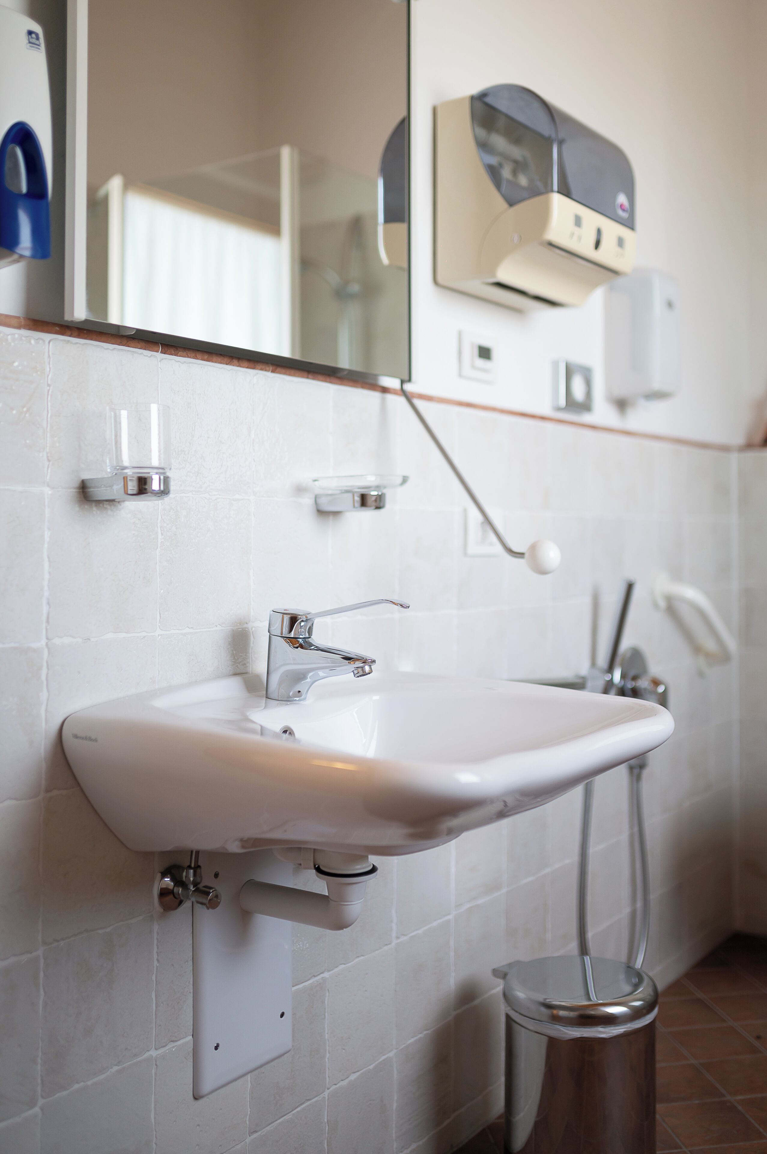 A bathroom with a white sink, mirror, and hand dryer.