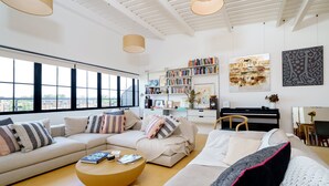 A modern living room with a sofa, a coffee table, and a bookshelf. - Super Spacious Penthouse in Art Deco Warehouse Conversion (London)