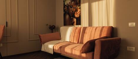 A modern living room with a sofa, a rug, and a painting on the wall.