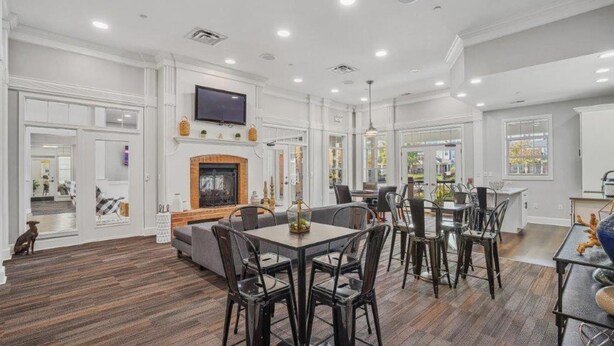 A spacious living room with a fireplace, dining area, and large windows. - Landing | Stylish 2BD, Pool, Tennis Court (West Dundee)