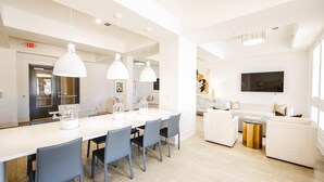 Een moderne keuken met witte aanrechtbladen, blauwe stoelen en hanglampen.