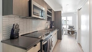 A modern kitchen with a hexagonal tile backsplash, stainless steel appliances, and wooden cabinetry.