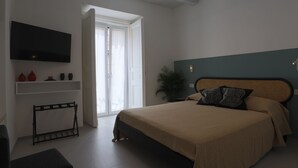 Un dormitorio moderno con cama, televisor, planta y banca.