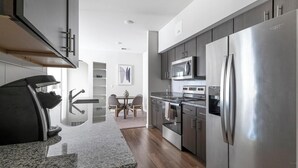 Una cucina moderna con elettrodomestici in acciaio inossidabile, una zona pranzo con tavolo in vetro e vista sul soggiorno.