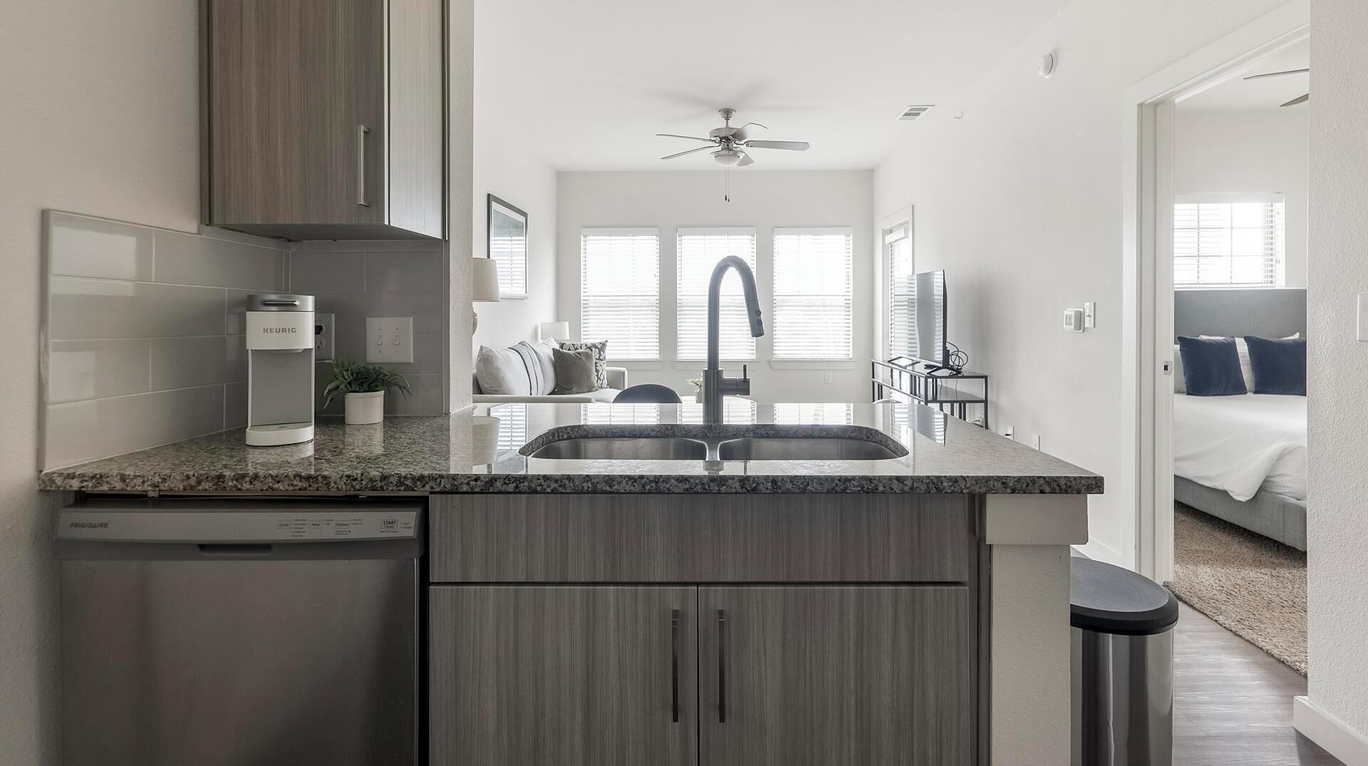 A modern kitchen with a dishwasher, a built-in oven, and a granite countertop.