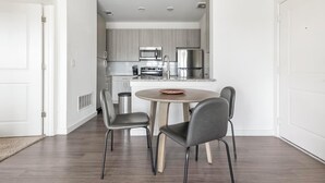 A modern kitchen with stainless steel appliances, a round dining table with four chairs, and a light-colored floor. - Landing | Chic 1BD, Clubhouse, Gym (Austin)