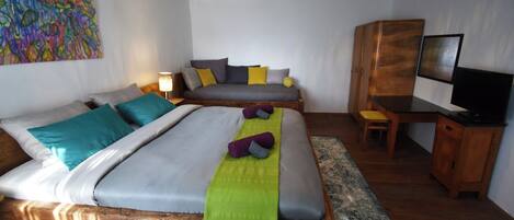 A modern bedroom with a large bed, a desk, and a TV.