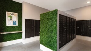 Una hall moderna con parete verde, una bacheca e file di armadietti neri.