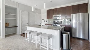 Una cocina moderna con una isla central, electrodomésticos de acero inoxidable y un cubo de basura.