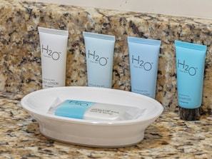 Four H2O Therapy body wash tubes and a white bowl with a blue towel on a granite countertop. - Downtown Friday Harbor! Newly Built! BL (Friday Harbor)