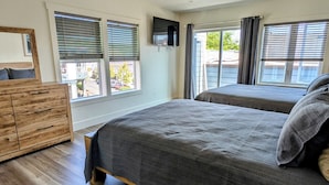 Un dormitorio con dos camas, un aparador de madera y una televisión en la pared.