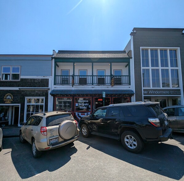 A building with a two-story structure, a covered porch, and a sign for a Chinese Teriyaki Sushi restaurant.