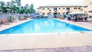 A swimming pool with lounge chairs and a barbecue area. - Aaron's Place (Enugu)