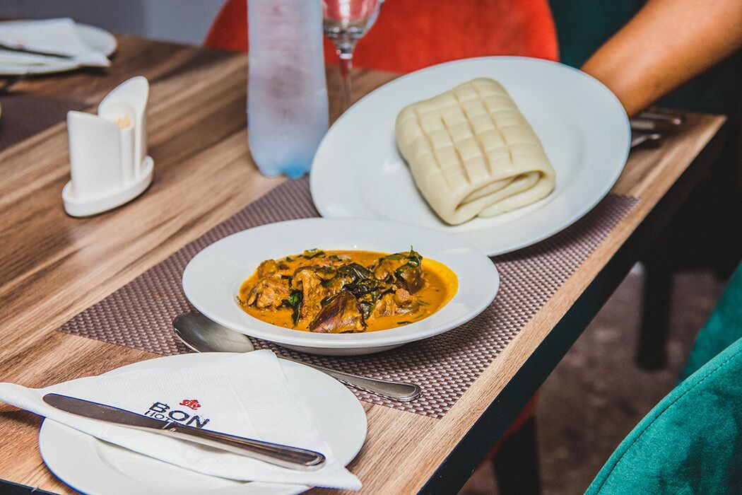 Uma mesa com uma refeição composta por um prato de curry, um item embalado e um prato com uma colher e guardanapo.
