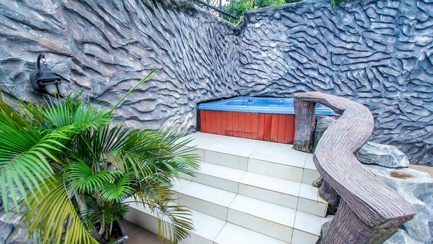 A staircase leading to a blue door, surrounded by a textured wall and a potted plant. - Aaron's Place (Enugu)