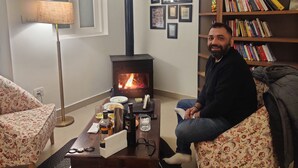 Una sala de estar acogedora con chimenea, una estantería y un sofá estampado con motivos florales.