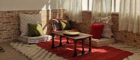 A cozy room with a brick wall, a wooden bench, and a red rug.