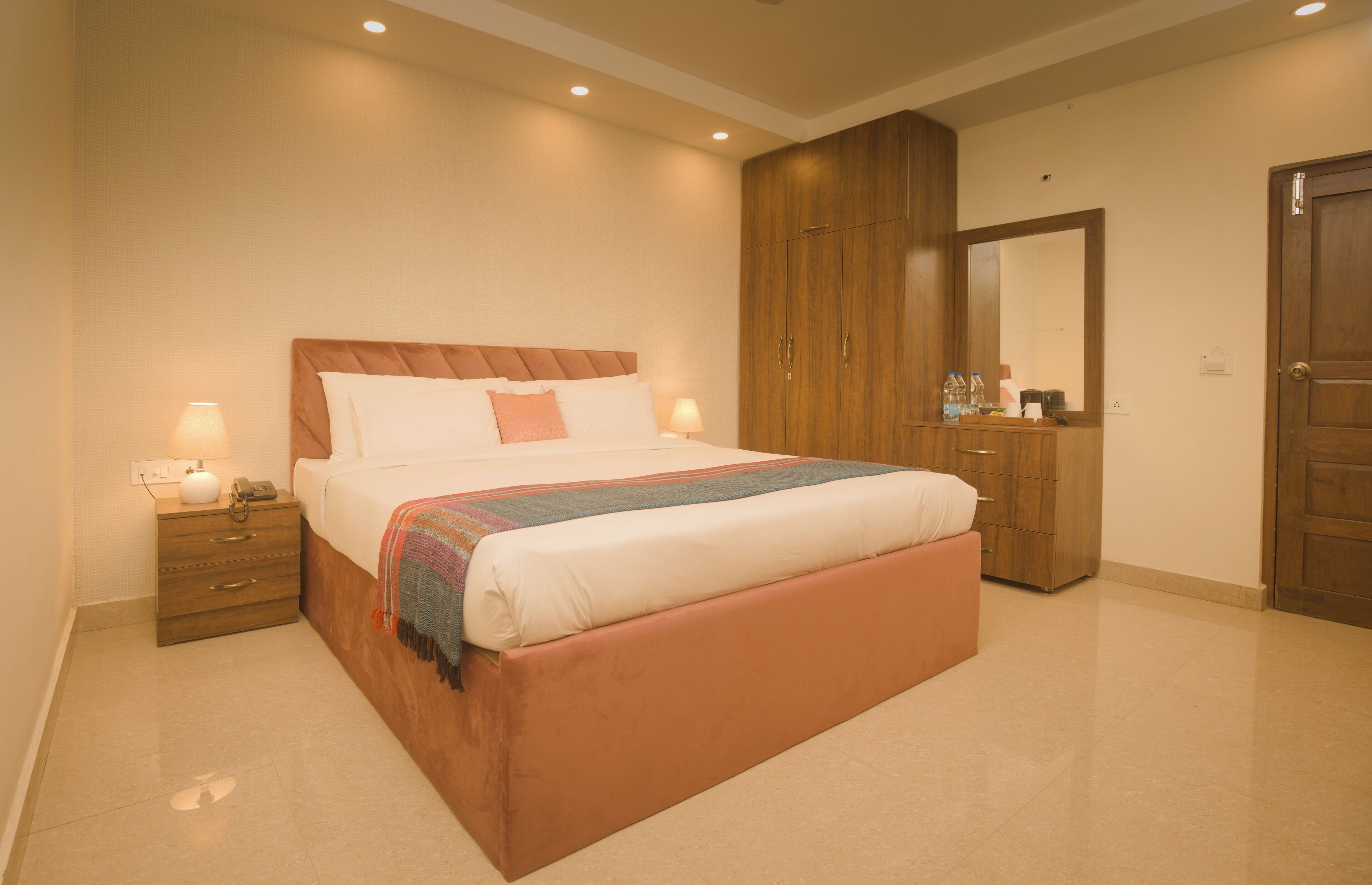 A bedroom with a bed, nightstand, dresser, and mirror.