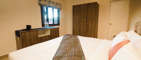 Un dormitorio con cama, escritorio, armario y ventana con cortina.