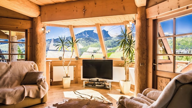 A wooden interior with a sofa, TV, and potted plants.